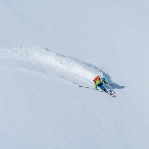 Skier descends powder snow slope in mountains